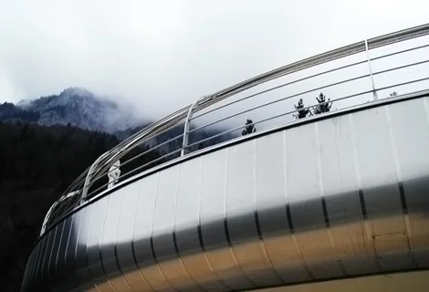 Gerundete Metallfassade vor bewaldeten Bergen
